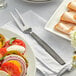 A plate of food with an American Metalcraft wavy aged stainless steel cold meat fork on a table.