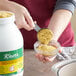 A person pouring yellow powder into a jar.