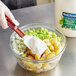 A gloved hand mixes Best Foods vegan mayonnaise into a bowl of food.