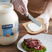 A person spreading Hellmann's Light Mayonnaise on a sandwich.