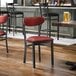 A black metal chair with a burgundy vinyl seat and backrest.