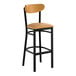 A black metal bar stool with a light brown vinyl seat and backrest.