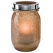 A glass jar with a tealight candle in a gold cradle.