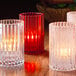 A group of red glass Hollowick vertical rod cylinders on a table.