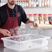 A man in an apron holding a clear polycarbonate tray over a clear polycarbonate food box.