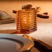 A Hollowick amber glass jewel candle holder on a table.