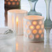 A close-up of a white porcelain votive with a striped pattern.