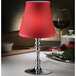 A close-up of a silver candle holder with a clear glass shade over a lit candle.