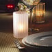 A Hollowick crystal candle lamp on a table with a white candle and a plate.