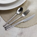 A Sola stainless steel table fork on a placemat next to a knife.