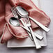 A close-up of a Sola Alessandria stainless steel dessert spoon on a white plate with silverware.