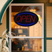 A Choice LED Open sign with lights on it hanging in a window.