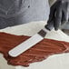 A person using an OXO Good Grips offset spatula to frost a cake.