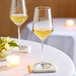 Two Zwiesel Glas Pure Sauvignon Blanc wine glasses on a table with a lit candle.