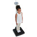 A young girl standing on a Cardinal Detecto digital clinical scale.