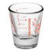 An Anchor Hocking clear measuring glass with orange print and graduations on a counter.