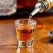 An Anchor Hocking measuring glass filled with brown liquid on a table.