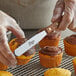 a person holding a knife over a cupcake