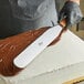 A person using an Ateco straight spatula to frost a cake.