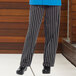 A person wearing Uncommon Chef black and white striped pants.