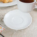 A white demitasse saucer with a cup of tea on it.