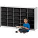 A young girl sitting on the floor next to a Rainbow Accents mobile storage cabinet reading a book.
