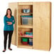 A woman in a teal shirt and black pants standing next to a Jonti-Craft wooden storage cabinet.
