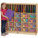 A girl standing next to a Jonti-Craft wood classroom organizer with clear plastic bins.