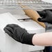 A person wearing Cordova brown jersey gloves opening a cardboard box.