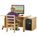 A child sitting at a Jonti-Craft computer desk with a white top using a computer.