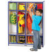 A young boy in a yellow jacket with red and blue text putting clothes in a Rainbow Accents navy and gray coat locker.