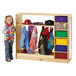 A girl standing next to a Jonti-Craft wood dress up storage cabinet with colored trays.