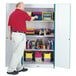 A man in a red shirt standing next to a Rainbow Accents teal storage closet.