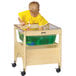 A child in a wooden stand with a clear tub playing with green water.