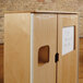 A wooden cabinet with a white door and a white board on it.