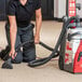 A woman using a Sanitaire upright carpet extractor to clean carpet.