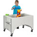 A boy playing with a Rainbow Accents sensory table filled with toys and water.