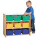 A child using a Jonti-Craft cubbie tray storage rack with colored bins to put toys away.