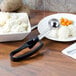 A Vollrath Jacob's Pride #30 black extended length squeeze handle ice cream scooper in a bowl of mashed potatoes.