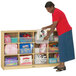 A woman putting items into a Jonti-Craft mobile wood storage cabinet.