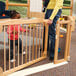 A woman standing behind a KYDZ Suite Welcome Gate with a child in a pink shirt and jeans.