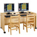 A Jonti-Craft natural wood double computer desk with two monitors and chairs.