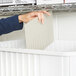 A person putting a piece of paper into a Short Metro gray tote box with dividers.