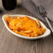 An ivory Hall China oval rarebit dish with pasta and cheese on a table.