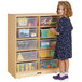 A little girl standing next to a Jonti-Craft wood storage unit with clear tubs.