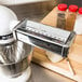 A KitchenAid stand mixer with pasta dough being cut.