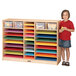 A girl standing next to a Jonti-Craft mobile wood paper center with shelves full of different colored paper.