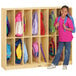 A young girl in a pink shirt standing in front of a Jonti-Craft locker with her backpack inside.