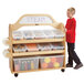 A boy pushing a Jonti-Craft wood cart with plastic bins on the shelves.