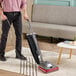 A man using a Sanitaire TRADITION lightweight upright vacuum cleaner to clean a carpet.